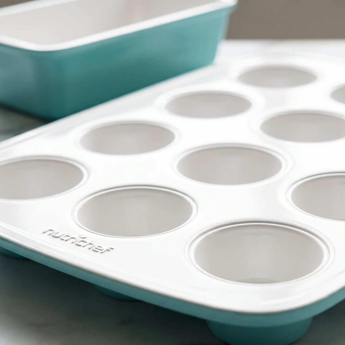 Close-up of the muffin cups and rolled rim of a NutriChef turquoise and white nonstick bakeware set