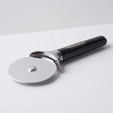 Farberware professional stainless steel pizza cutter wheel with black comfort grip handle and finger guard on a studio surface