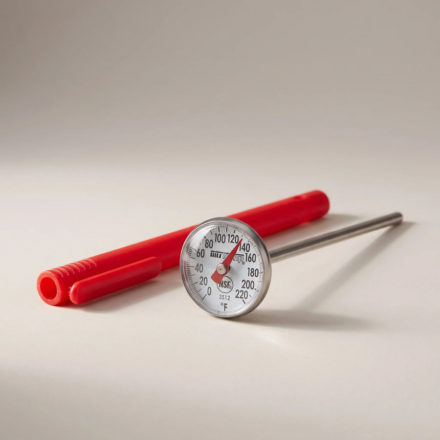 Taylor 3512 instant read dial thermometer with stainless steel stem, magnified dial and red pocket sleeve on a studio surface