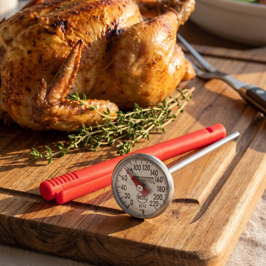 Taylor instant read dial thermometer on a carving board beside a golden roast chicken