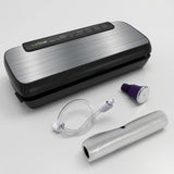 NutriChef automatic vacuum sealer with brushed stainless steel lid, suction hose, wine stopper and bag roll on a studio surface