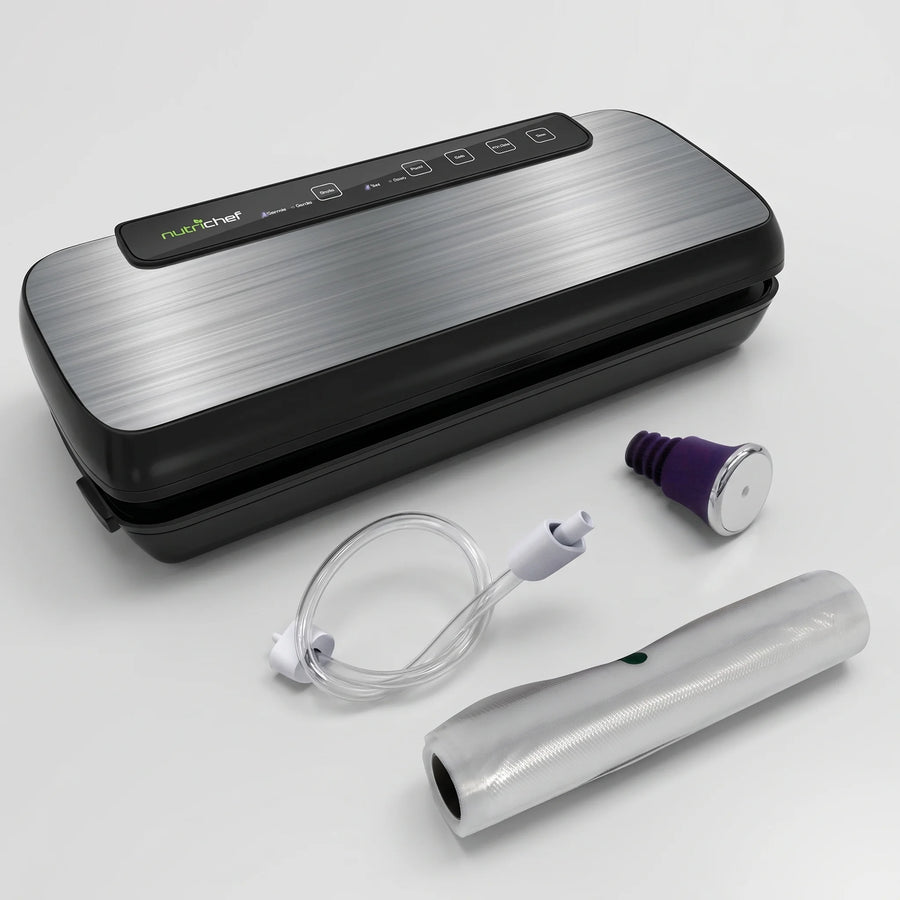 NutriChef automatic vacuum sealer with brushed stainless steel lid, suction hose, wine stopper and bag roll on a studio surface