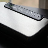 Close-up of the brushed stainless steel lid and touch control buttons of a NutriChef automatic vacuum sealer