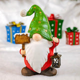 Christmas garden gnome holding a wooden sign and a lantern, wearing a tall green star hat and a white beard